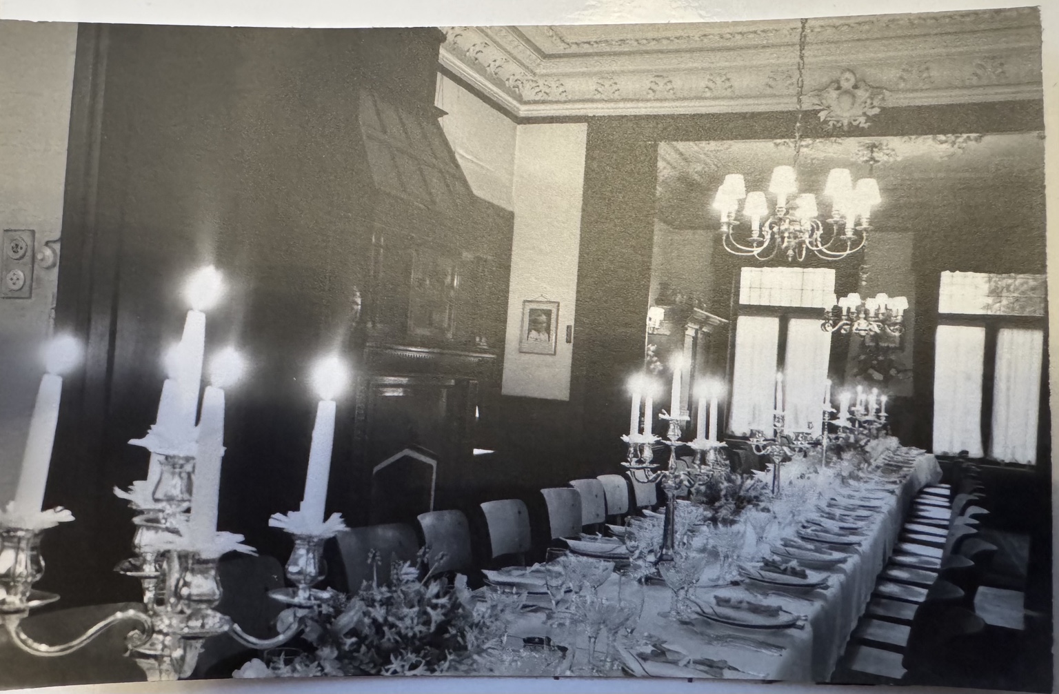 Een feestelijk gedekte tafel in de villa, met schouw, kroonluchters en ornamentplafond. Datum en gelegenheid onbekend.